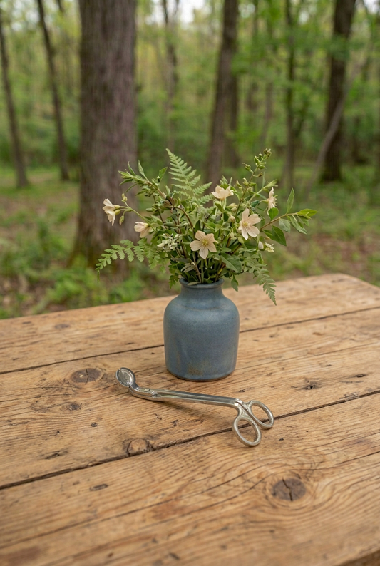 Trimmer on an old pine table with a vintage blue vase and woodland flowers